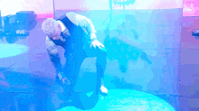 a man is kneeling down in front of a purple and blue background