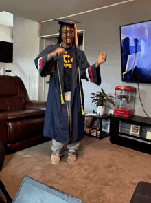 a man in a graduation cap and gown dancing in a living room