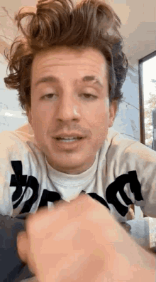 a close up of a man with a mustache wearing a sweater and making a face .