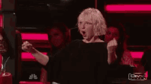 a woman in a black shirt is raising her fist in the air ..