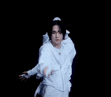 a man in a white hoodie is surrounded by hands
