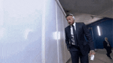 a man in a suit and tie is walking down a hallway with headphones on his head