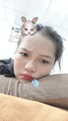 a girl with a sad face and a cartoon rabbit on her head