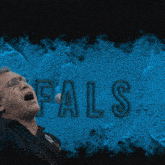 a man singing in front of a blue wall that says fals