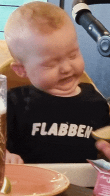 a baby wearing a black shirt that says flabbeh
