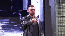 a man wearing sunglasses and a black leather jacket is pointing