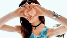 a woman is making a heart shape with her hands over her face .