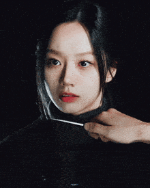 a close up of a woman 's face with a hand holding a conductor 's stick