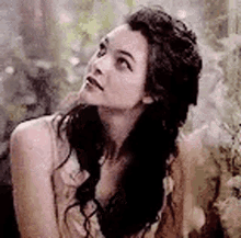 a woman with long black hair is looking up at the sky .