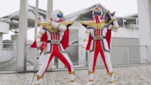 a couple of superheros standing next to each other in front of a building