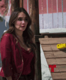 a woman in a red top is standing on a wooden deck with a red t on it