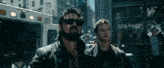 two men wearing sunglasses and a shirt that says us are walking down a city street