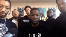 a group of men are posing for a picture and the number 24 is on the wall behind them