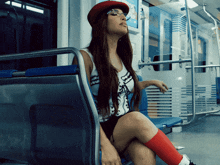 a woman wearing a red hat and glasses is sitting on a train