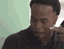 a man is applying lotion to his face while looking at his phone .