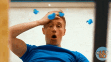 a man in a blue shirt has a surprised look on his face behind him is a multi do logo