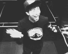 a black and white photo of a man wearing a hat and a t-shirt .