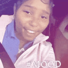 a woman is sitting in a car wearing a pink jacket and smiling .