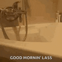 a bathtub with a shower head attached to it and the words `` good mornin ' lass '' written on the bottom .