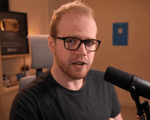 a man wearing glasses stands in front of a sennheiser microphone