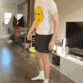 a man in a white shirt with a yellow face on it is standing in a living room