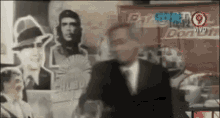a man in a suit and tie stands in front of a wall with pictures of che guevara