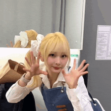 a girl with blonde hair is waving her hands in front of a fridge