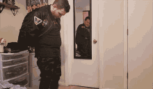 a man standing in front of a mirror wearing a nasa jacket