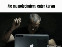 a man sitting in front of an apple laptop with the words " ale mu pojechatem enter kurwa " on the bottom