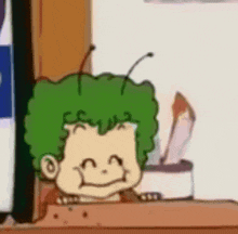 a cartoon character with green hair and antennas is sitting on a table .