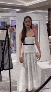 a woman in a white dress is standing in front of a mirror .