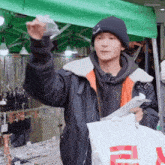 a man wearing a black beanie is holding a white bag with a red r on it ..