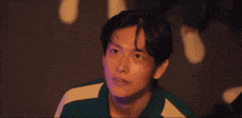 a man in a green and white shirt is looking at something