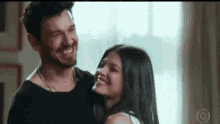 a man and woman are hugging each other and smiling .