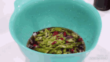 a blue bowl filled with green peppers and red peppers is being made in animatica