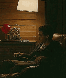 a man is sitting in a chair with a lamp in the background .