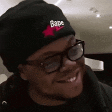 a man wearing glasses and a black beanie with the word bape on it