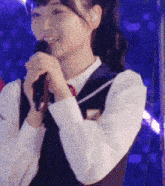 a girl in a school uniform is holding a microphone
