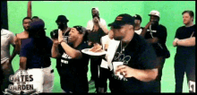 a group of people are gathered in front of a green screen with the words gates in the garden on the bottom