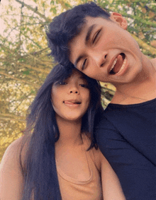 a boy and a girl are posing for a picture with their tongues out