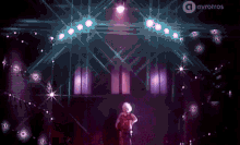 a woman is standing on a stage with a lot of lights behind her