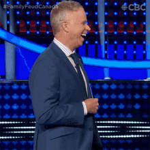 a man in a blue suit and tie is laughing on a stage .