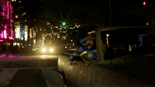 a woman is sitting in a car at night with a green light behind her