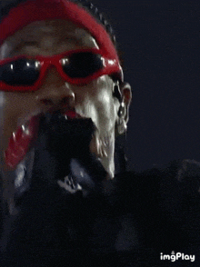 a close up of a man wearing red sunglasses and a headband .