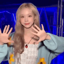 a woman with blonde hair is wearing a blue sweater and a necklace and making a funny face .