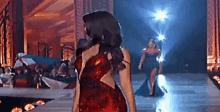 a woman in a red dress is walking down a runway at a fashion show .