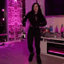 a woman is dancing in a living room with purple lights