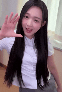 a young woman with long black hair is waving her hand