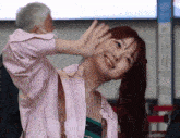 a woman in a pink shirt is waving her hand and smiling