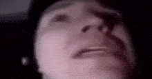 a close up of a person 's face in a dark room looking up at the sky .